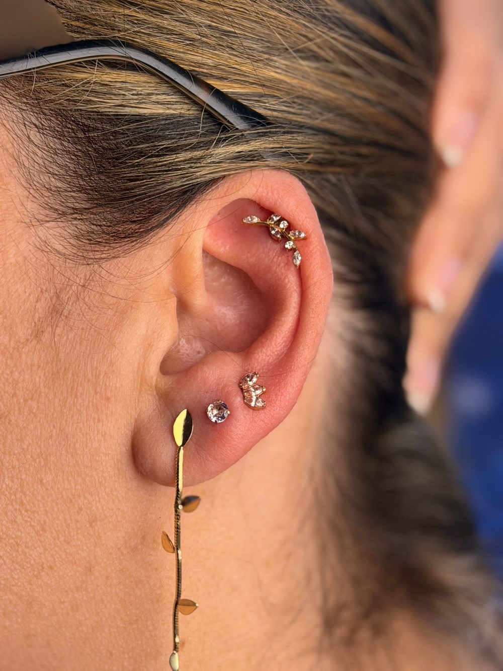 Composição de piercings em orelha de adulto com joias de ouro e visagismo auricular (helix e lóbulo) na Luquini Clinic, Rio de Janeiro