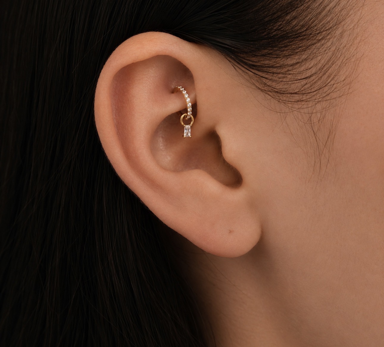 Piercing rook com argola de ouro cravejada e pingente na dobra interna da cartilagem da orelha — Luquini Estética Auricular