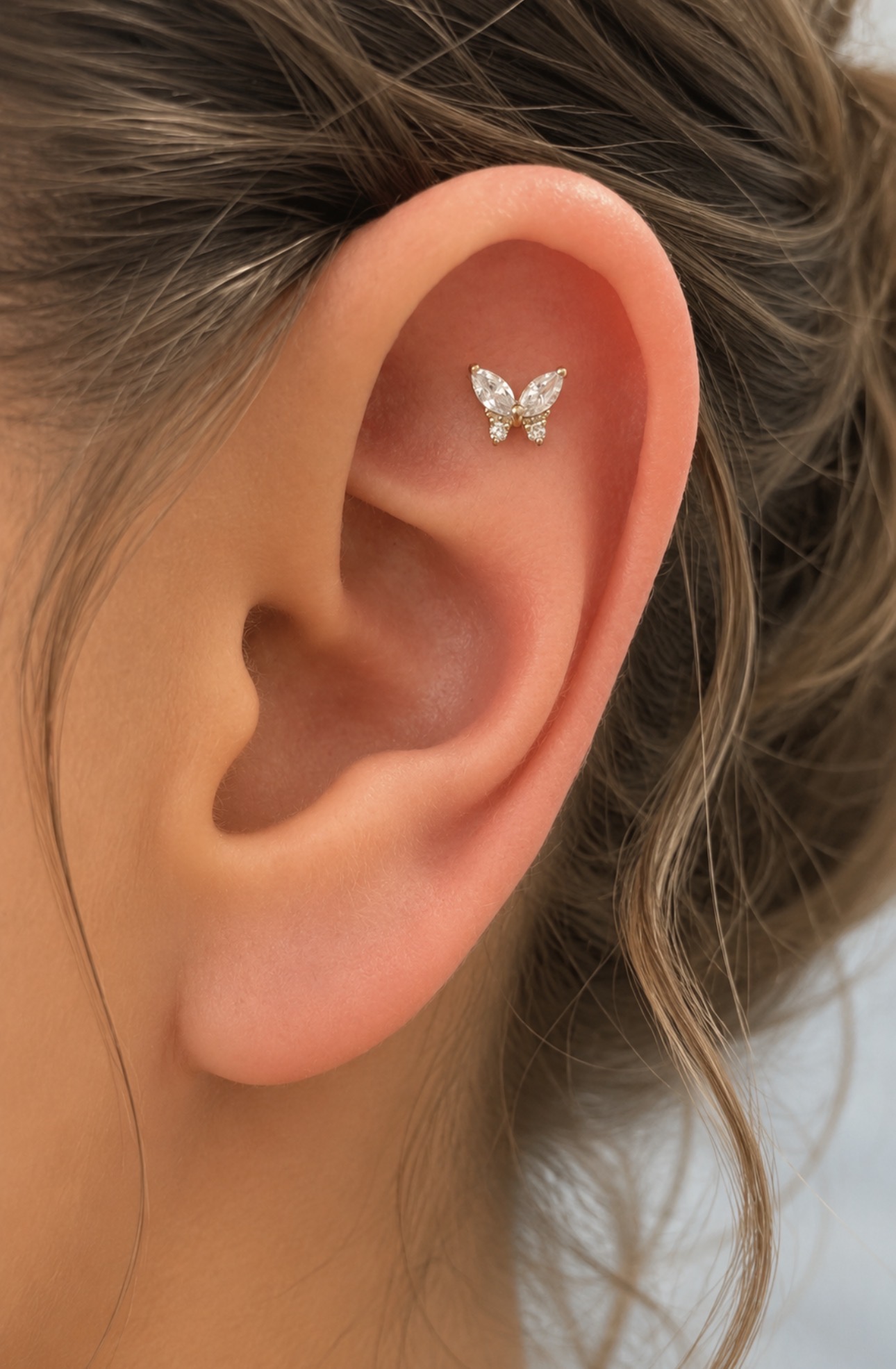 Piercing flat com joia de borboleta em ouro e zircônias na escafa superior da orelha — Luquini Estética Auricular