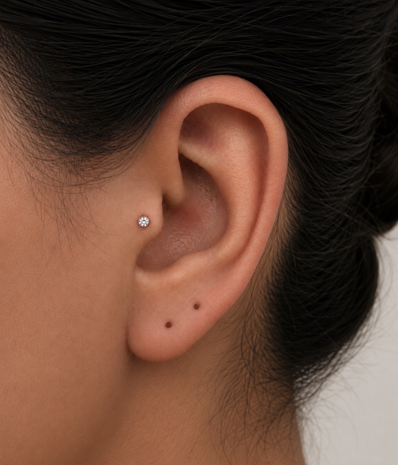 Piercing tragus com joia de zircônia na entrada do canal auditivo, feito pela Luquini com técnica de perfuração humanizada